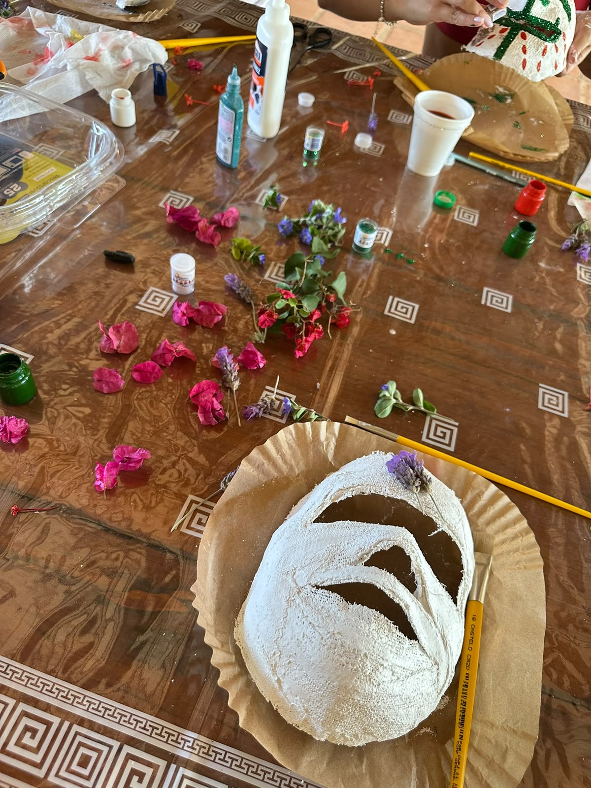 Máscara de gesso sendo decorada com flores secas e tintas